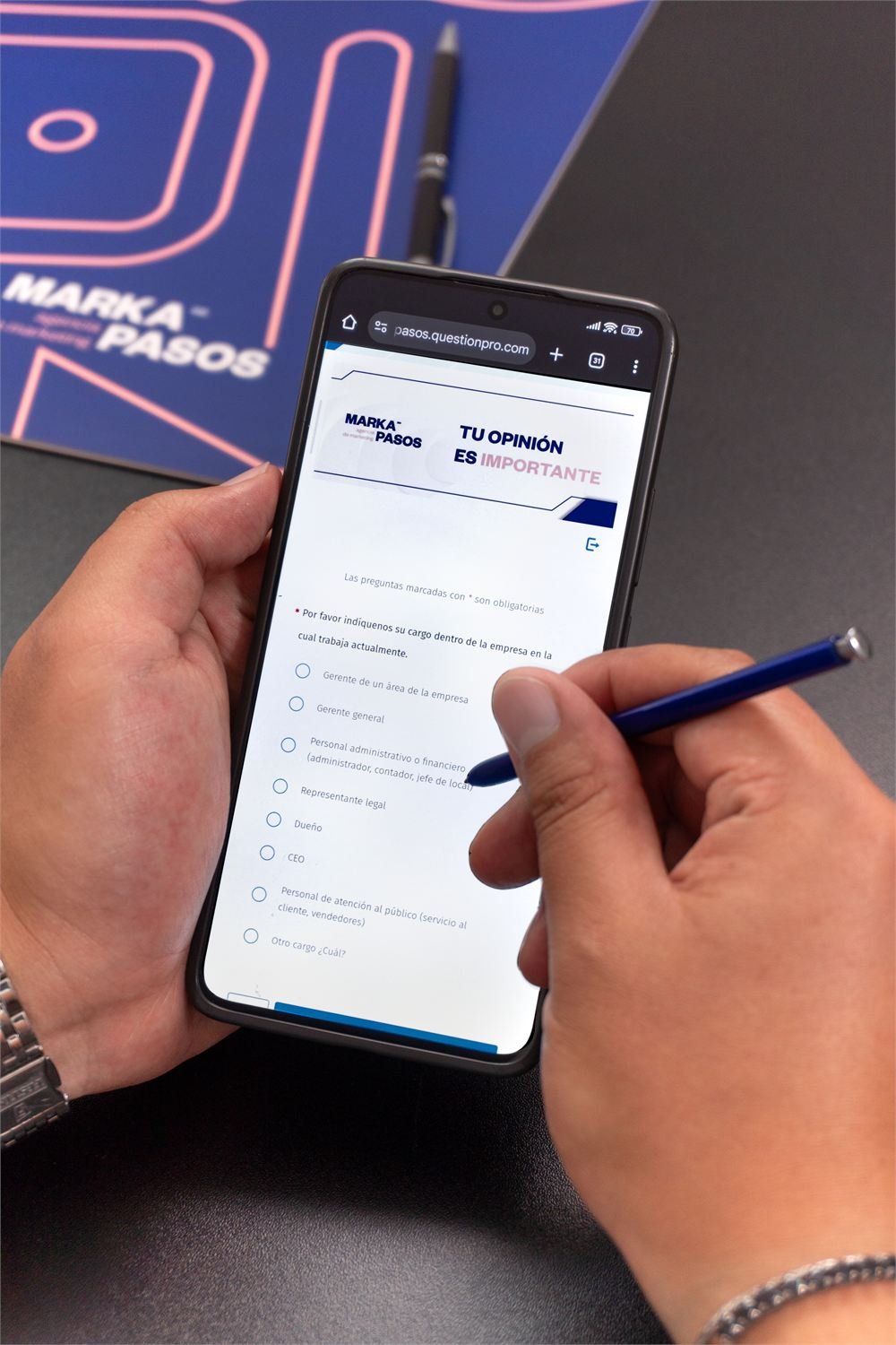 Manos con un celular que muestra una encuesta de Markapasos